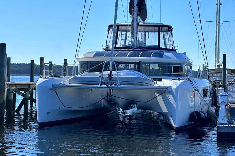 The Image of 2023 Lagoon 50 catamaran docked at marina, clear blue sky, calm water. - 0