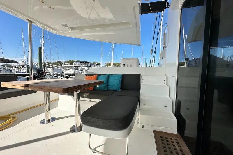 Slide: The Image of 2023 Lagoon 50 yacht deck with seating, table, and marina view. - 19