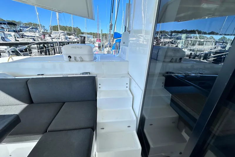 Slide: The Image of 2023 Lagoon 50 yacht interior with seating and stairs, docked at marina. - 3