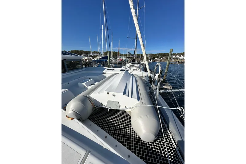 Slide: The Image of 2023 Lagoon 50 catamaran docked at marina, featuring spacious deck and inflatable dinghy. - 40
