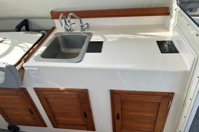 Slide: The Image of 2018 C-Dory 23' Venture boat kitchenette with sink, faucet, and wooden cabinets. - 11