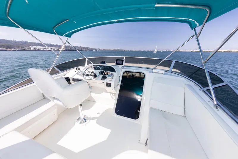 Slide: The Image of 2004 Meridian 490 Pilothouse boat interior with steering wheel and seating, under blue canopy. - 12