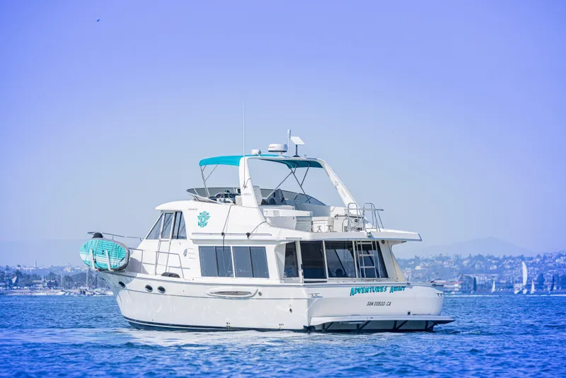 Slide: The Image of 2004 Meridian 490 Pilothouse yacht cruising on calm waters with cityscape background. - 3