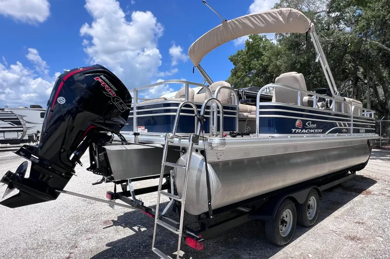 The Image of 2023 Sun Tracker Fishin' Barge 22 DLX pontoon boat with outboard motor on trailer. - 0