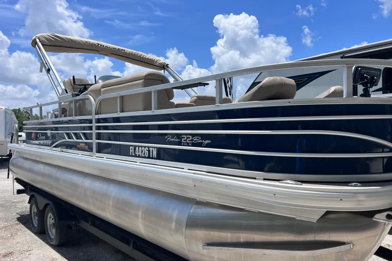 Slide: The Image of 2023 Sun Tracker Fishin' Barge 22 DLX pontoon boat on trailer under blue sky. - 10