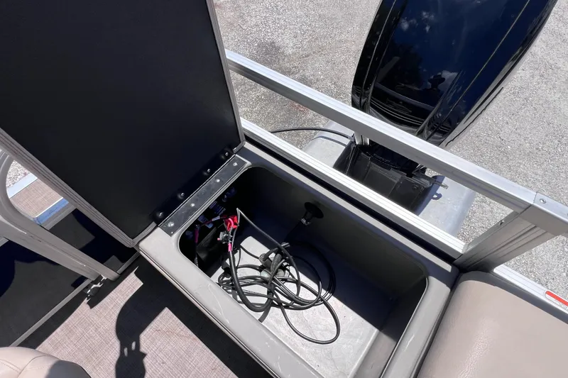 Slide: The Image of 2023 Sun Tracker Fishin' Barge 22 DLX storage compartment with cables and equipment. - 16