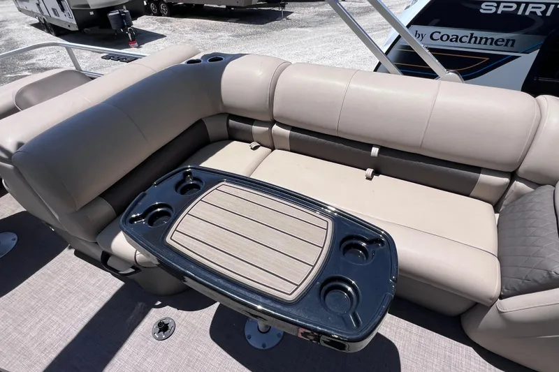 Slide: The Image of 2023 Sun Tracker Fishin' Barge 22 DLX interior with beige seating and table. - 19