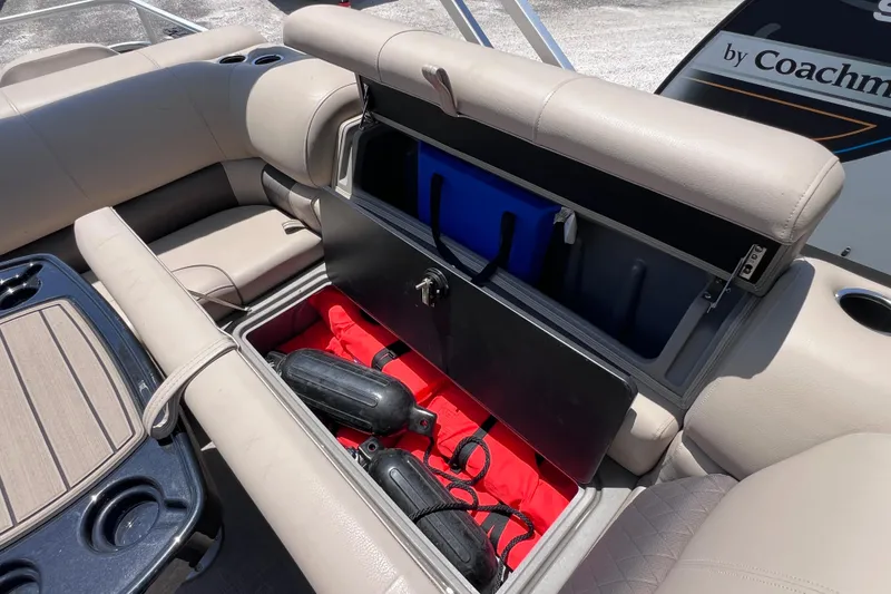 Slide: The Image of 2023 Sun Tracker Fishin' Barge 22 DLX storage compartment with safety gear and cooler. - 20