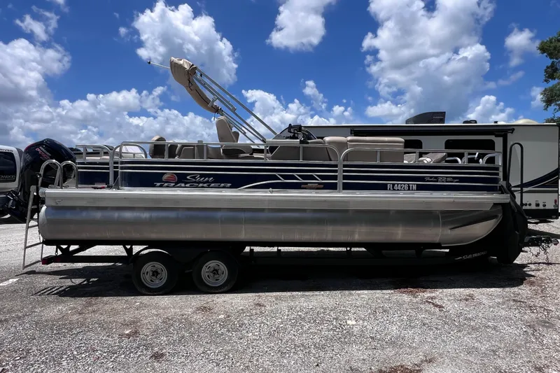Slide: The Image of 2023 Sun Tracker Fishin' Barge 22 DLX pontoon boat on trailer under blue sky. - 3