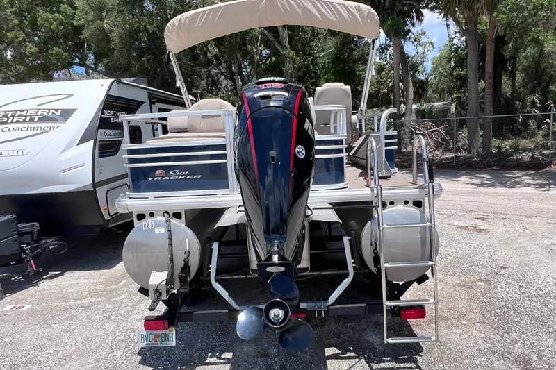 Slide: The Image of 2023 Sun Tracker Fishin' Barge 22 DLX pontoon boat with outboard motor, parked outdoors. - 4