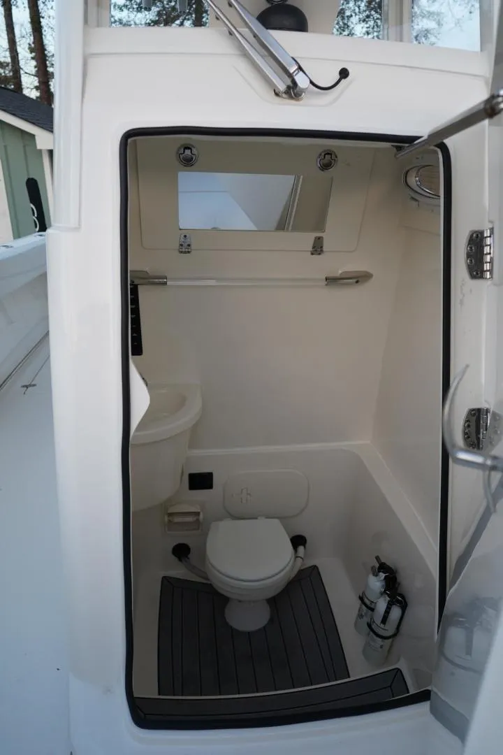 Slide: The Image of 2022 Cobia 266 boat interior with compact marine toilet and window. - 23