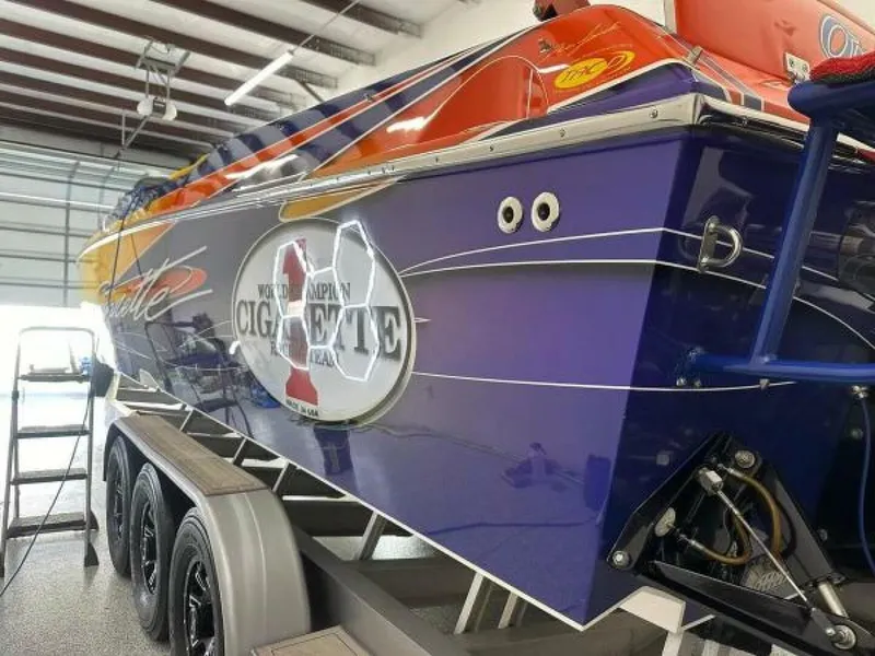 Slide: The Image of 2005 Cigarette 39 Top Gun speedboat in garage, vibrant blue and orange design, on trailer. - 12