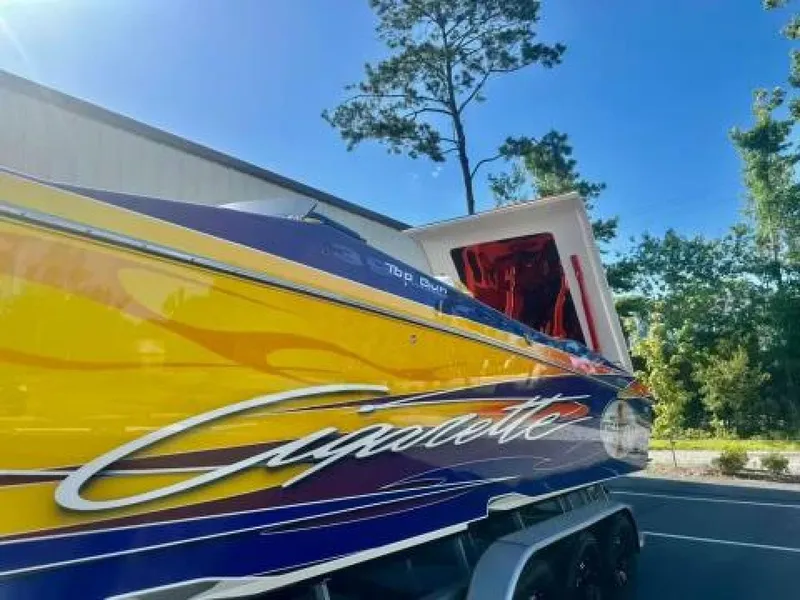 Slide: The Image of 2005 Cigarette 39 Top Gun boat with vibrant yellow and blue design, parked outdoors. - 4