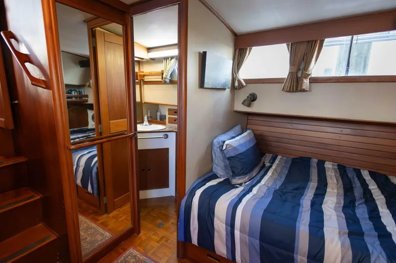 Slide: The Image of Cozy cabin interior of 1985 Grand Banks 42 Classic yacht with striped bedding and wooden accents. - 13