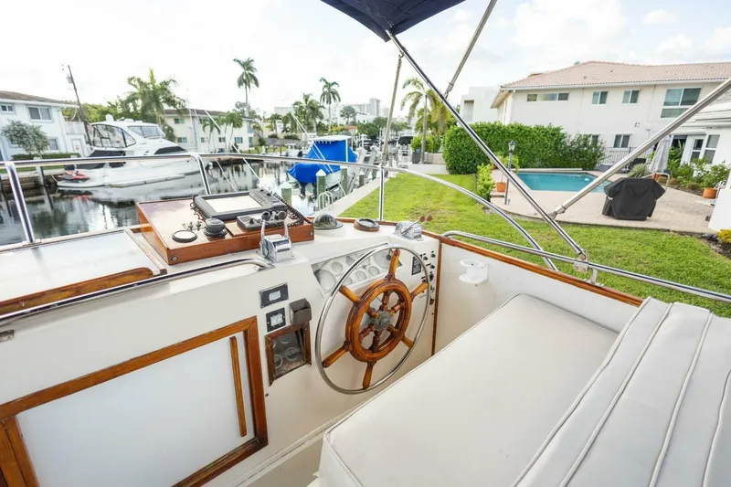Slide: The Image of Cockpit of 1985 Grand Banks 42 Classic yacht with wooden steering wheel and marina view. - 31