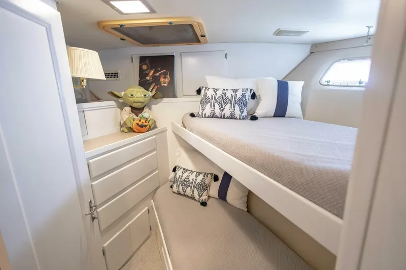 Slide: The Image of 1989 Hatteras Custom Cockpit cabin with cozy bed, decorative pillows, and playful decor. - 43