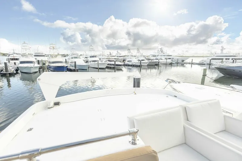 Slide: The Image of 1989 Hatteras Custom Cockpit yacht docked in a marina under a bright, cloudy sky. - 49