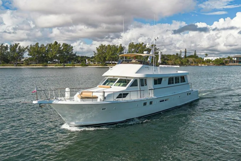 Slide: The Image of 1989 Hatteras Custom Cockpit yacht cruising on a scenic waterway under a cloudy sky. - 8