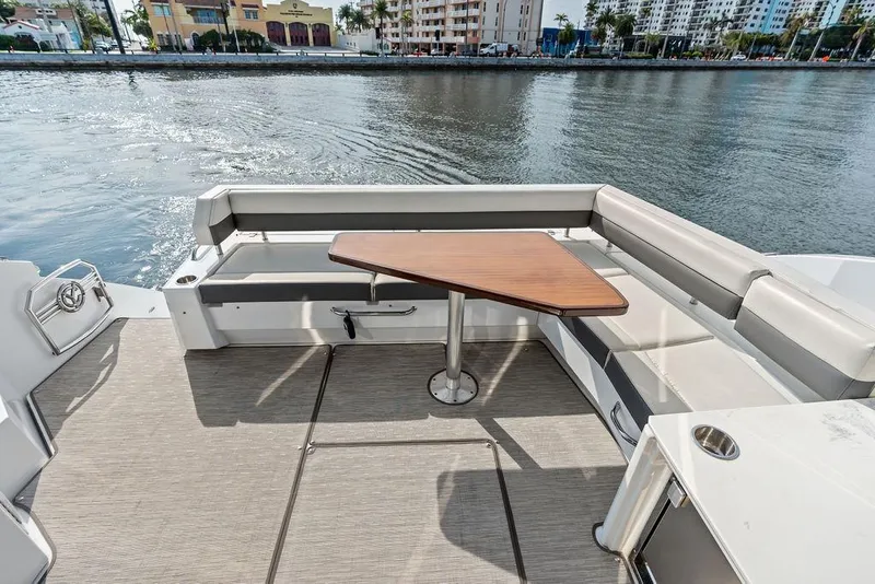 Slide: The Image of Sleek 2022 Cruisers Yachts 46 Cantius deck with seating and table, overlooking waterfront. - 12