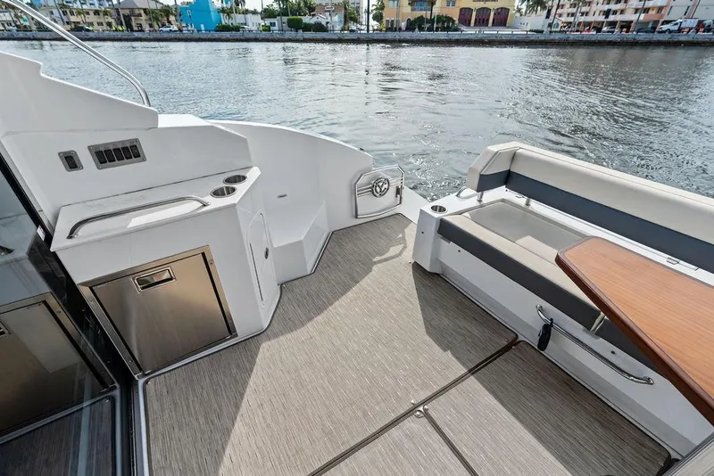 Slide: The Image of 2022 Cruisers Yachts 46 Cantius deck with seating and kitchenette by the water. - 13