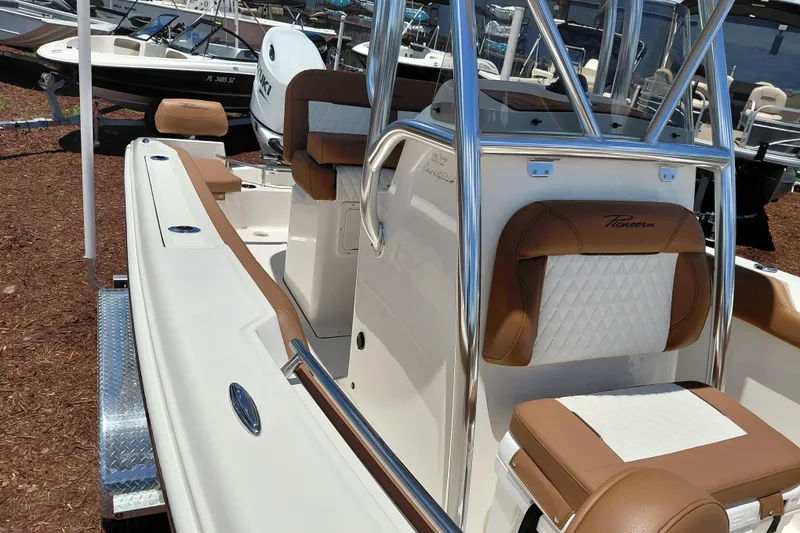 Slide: The Image of 2026 Pioneer 202 Sportfish boat with brown and white seating, docked outdoors. - 17