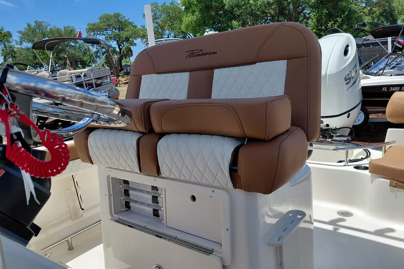 Slide: The Image of 2026 Pioneer 202 Sportfish boat seat with brown and white upholstery, steering wheel, and outdoor setting. - 27