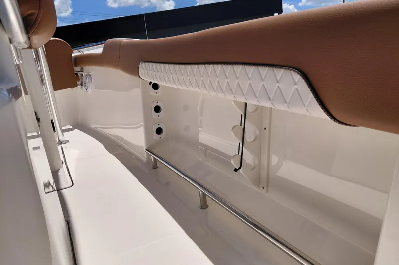 Slide: The Image of 2026 Pioneer 202 Sportfish interior with cushioned seating and rod holders under sunny skies. - 35