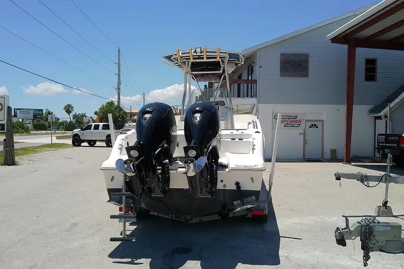 Slide: The Image of 2003 Wellcraft 250 Fisherman boat with dual outboard motors parked outside a building. - 2