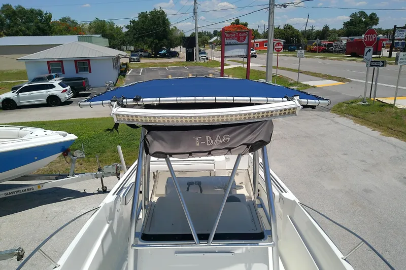 Slide: The Image of 2003 Wellcraft 250 Fisherman boat with blue canopy, parked on a trailer in a lot. - 26