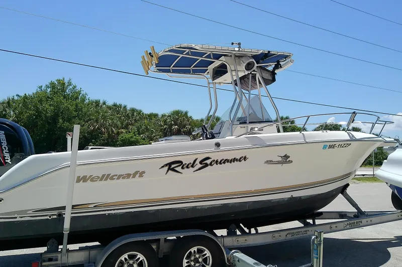 Slide: The Image of 2003 Wellcraft 250 Fisherman boat on trailer, side view with trees in background. - 5