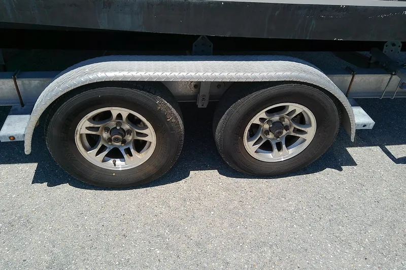 Slide: The Image of Trailer wheels for 2003 Wellcraft 250 Fisherman boat on asphalt surface. - 9