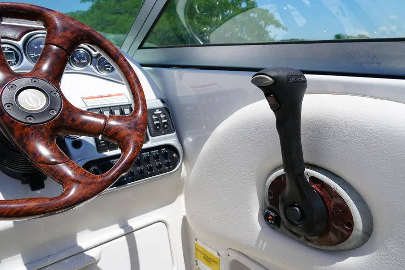 Slide: The Image of 2004 Crownline 250 CR boat dashboard with woodgrain steering wheel and throttle control. - 11