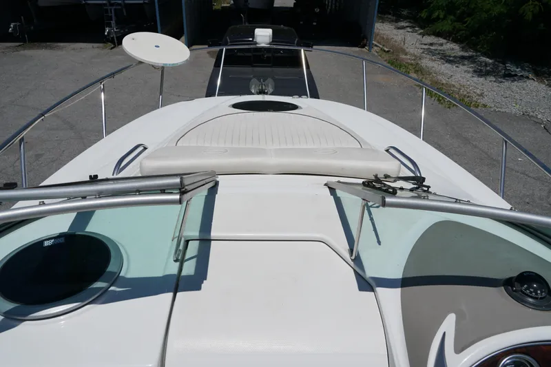 Slide: The Image of 2004 Crownline 250 CR boat deck with sun pad and railing, parked on pavement. - 14