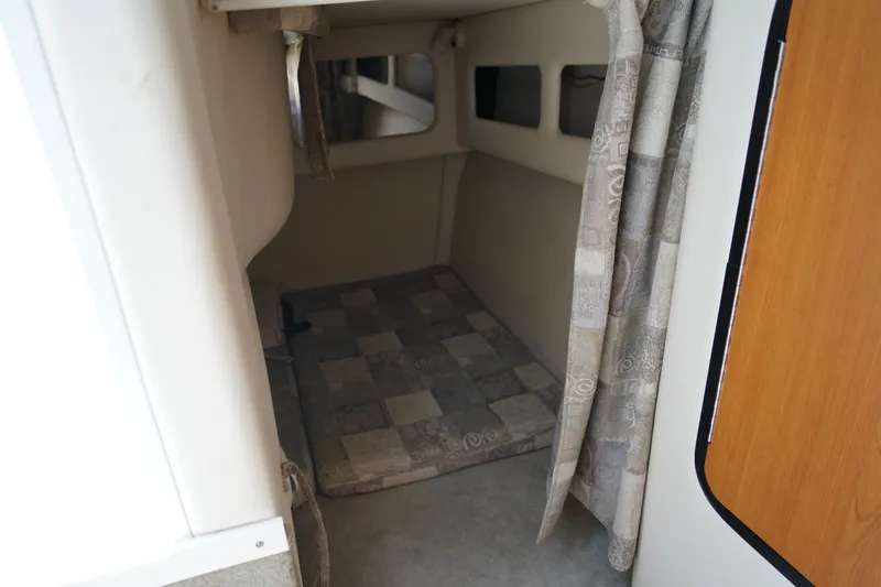 Slide: The Image of 2004 Crownline 250 CR cabin interior with patterned curtains and cushioned flooring. - 22