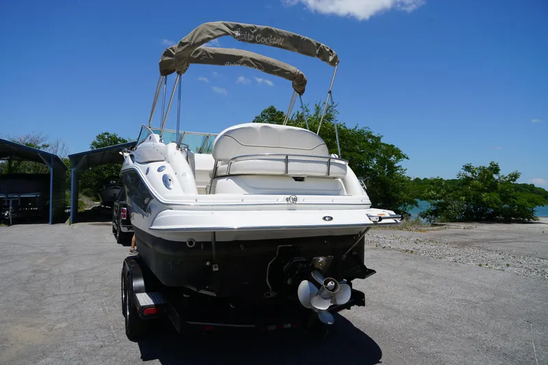 Slide: The Image of 2004 Crownline 250 CR boat on trailer, parked near a lake under a clear blue sky. - 3