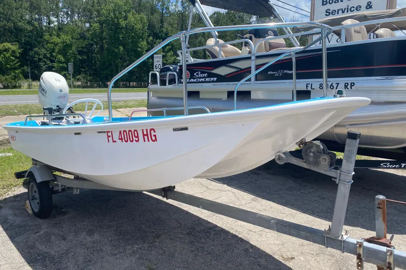 The Image of 1959 Boston Whaler 13 boat on trailer, parked near a road with trees in background. - 1