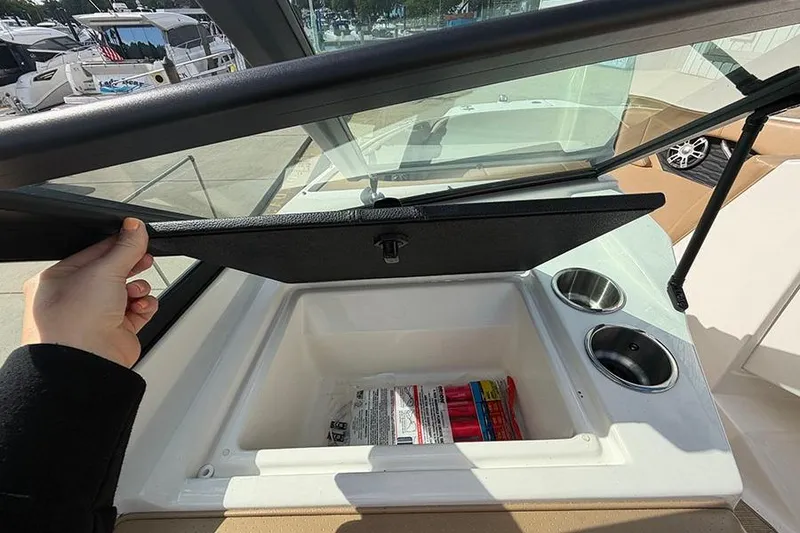 Slide: The Image of 2021 Sea Ray SPX 210 boat storage compartment with cup holders and safety items. - 20