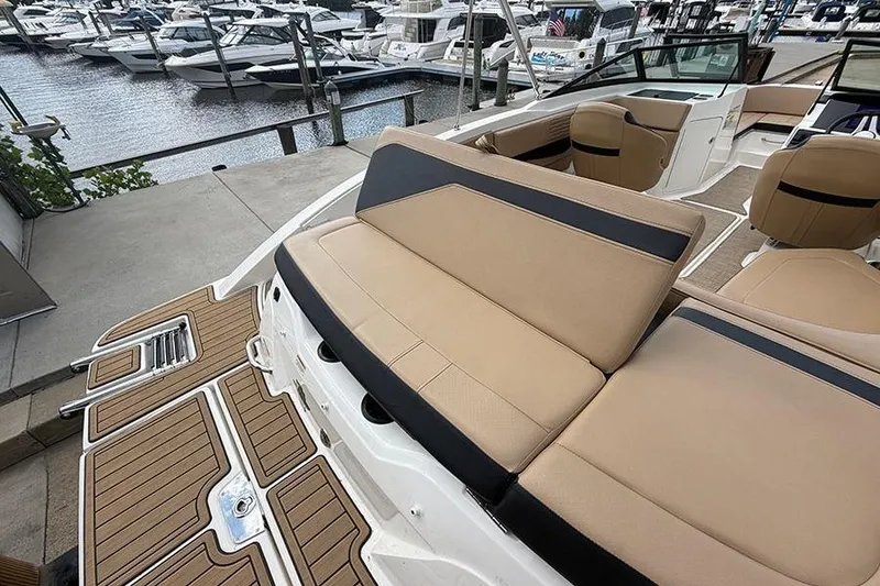 Slide: The Image of 2021 Sea Ray SPX 210 boat interior with tan seating and docked boats in the background. - 8