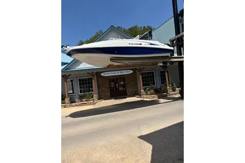 Slide: The Image of 2020 Tahoe 2150 CC boat suspended outside a building on a sunny day. - 2