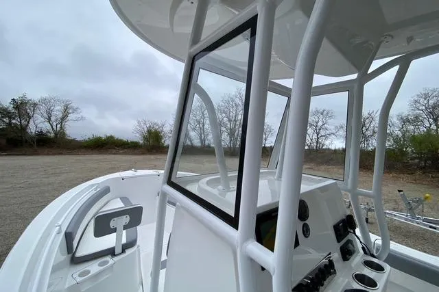 Slide: The Image of White 2021 Release 210 RX boat interior with console and seating, parked outdoors. - 11