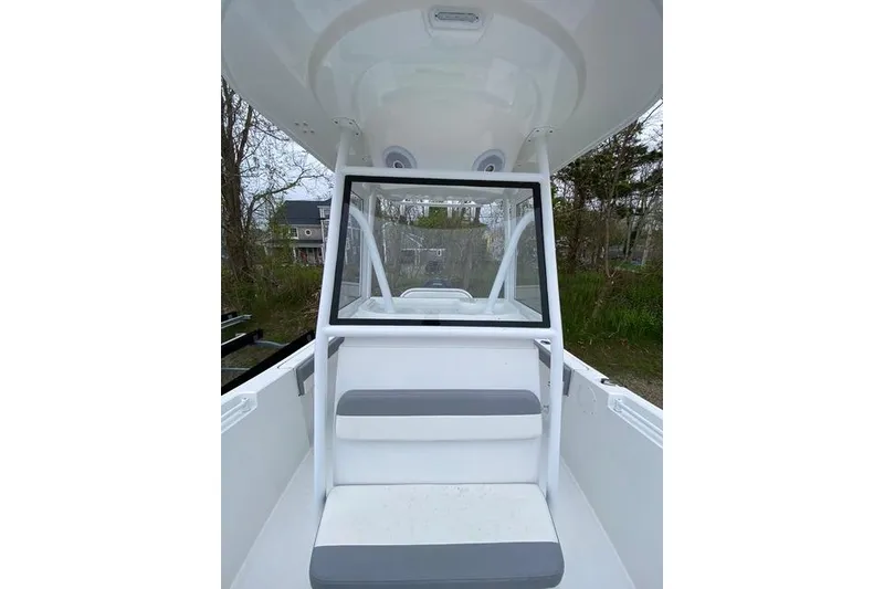 Slide: The Image of 2021 Release 210 RX boat interior with seating and windshield, surrounded by trees. - 18
