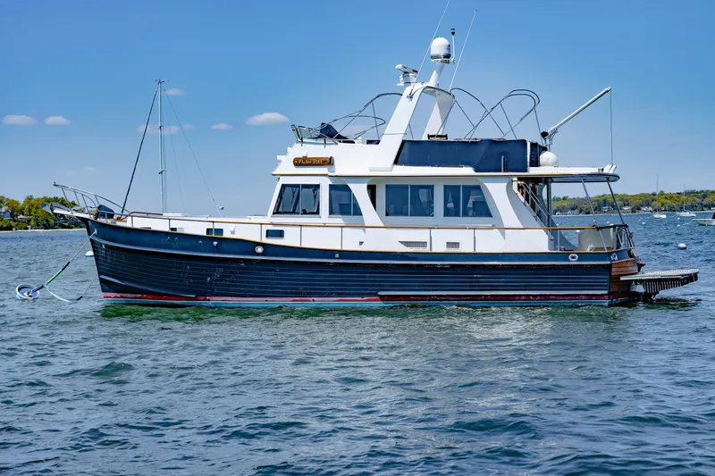 The Image of 2002 Grand Banks 46 Europa yacht on calm water under clear blue sky. - 0