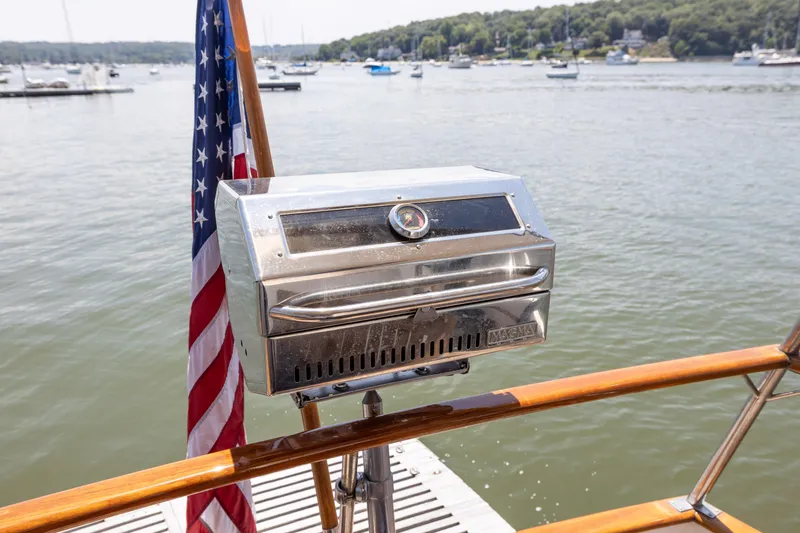 Slide: The Image of Outdoor grill on a 2002 Grand Banks 46 Europa yacht with American flag, docked by the water. - 23