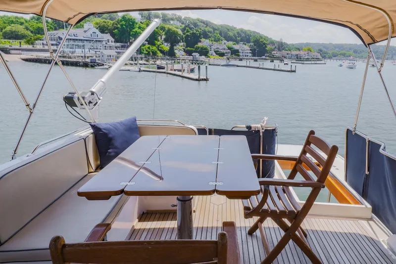 Slide: The Image of Deck view of 2002 Grand Banks 46 Europa yacht with seating and table, overlooking marina. - 3