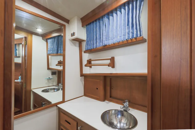 Slide: The Image of Bathroom interior of 2002 Grand Banks 46 Europa yacht with wooden cabinetry and blue curtains. - 6