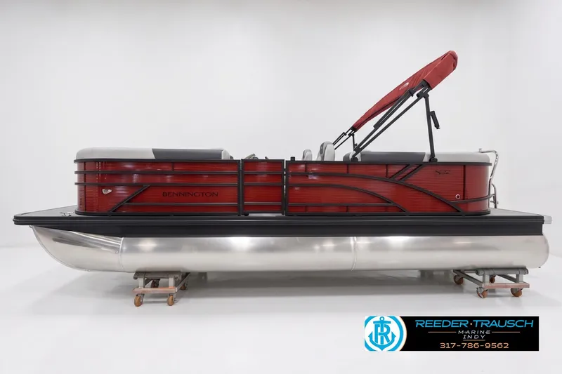 The Image of 2026 Bennington 22 S1SR pontoon boat with red exterior and canopy, displayed indoors. - 1