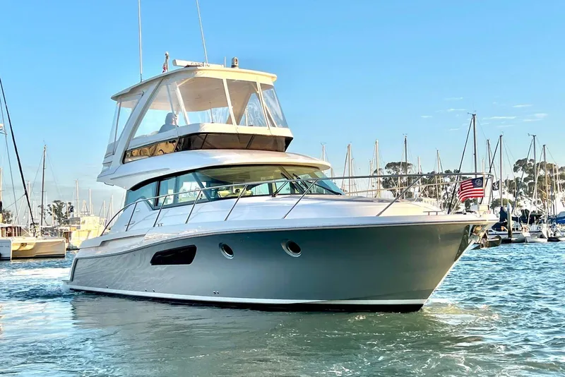 The Image of 2019 Tiara Yachts F44 Flybridge cruising in a marina with clear blue skies. - 0