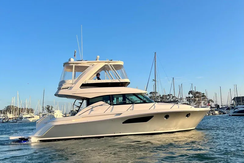Slide: The Image of 2019 Tiara Yachts F44 Flybridge cruising in a marina under clear blue skies. - 1