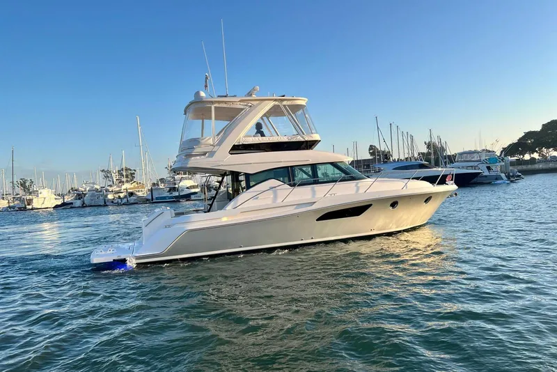 Slide: The Image of 2019 Tiara Yachts F44 Flybridge cruising in a marina at sunset. - 10