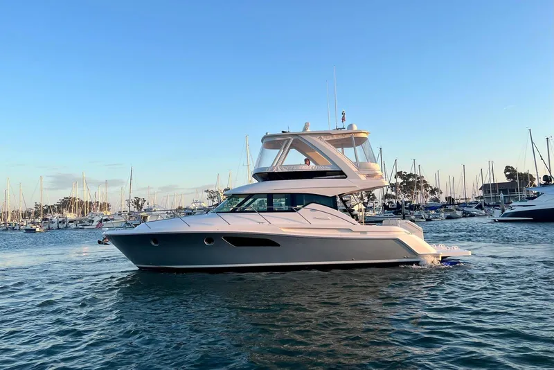 Slide: The Image of 2019 Tiara Yachts F44 Flybridge cruising in a marina at sunset. - 12